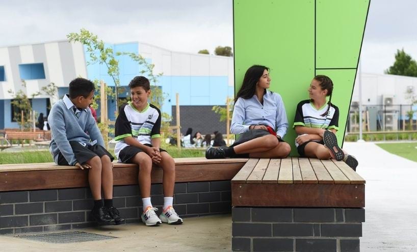 Four students sitting outside in school playground Four students sitting outside in school playground