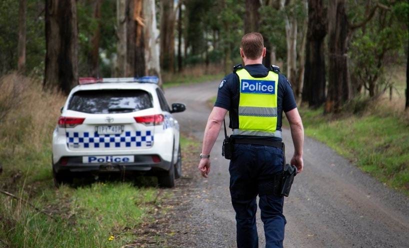 Police officer walking towards car on regional road Police officer walking towards car on regional road